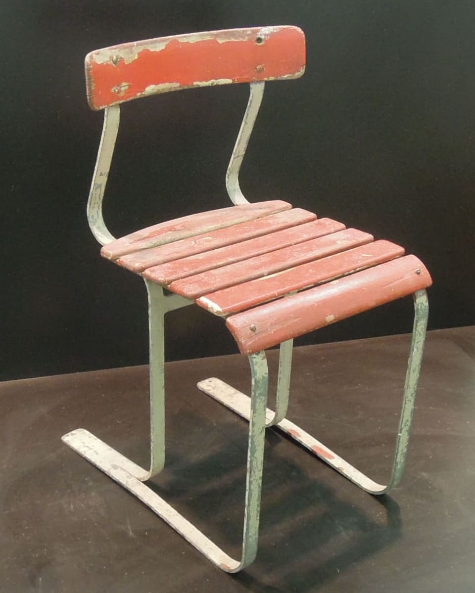Einfacher Stuhl aus Metall und rot lackierten Holzlatten.