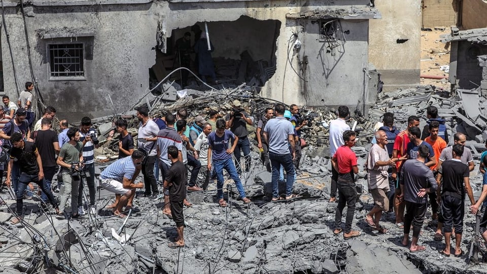 Menschen stehen auf den Trümmern eines zerstörten Hauses in Gaza-Stadt