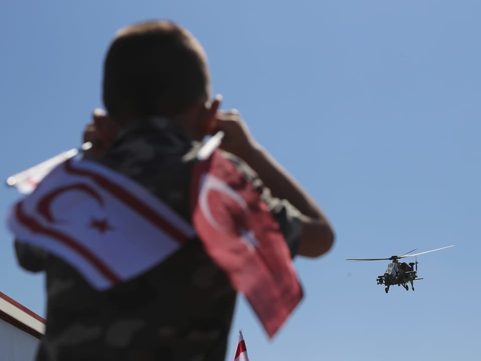 Ein Bub mit türkischen Fahnen schaut auf einen Militärhelikopter. 