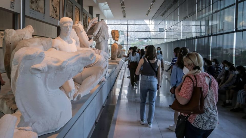Besuchende schauen sich in Athener Museum den Parthenon-Frist an. 