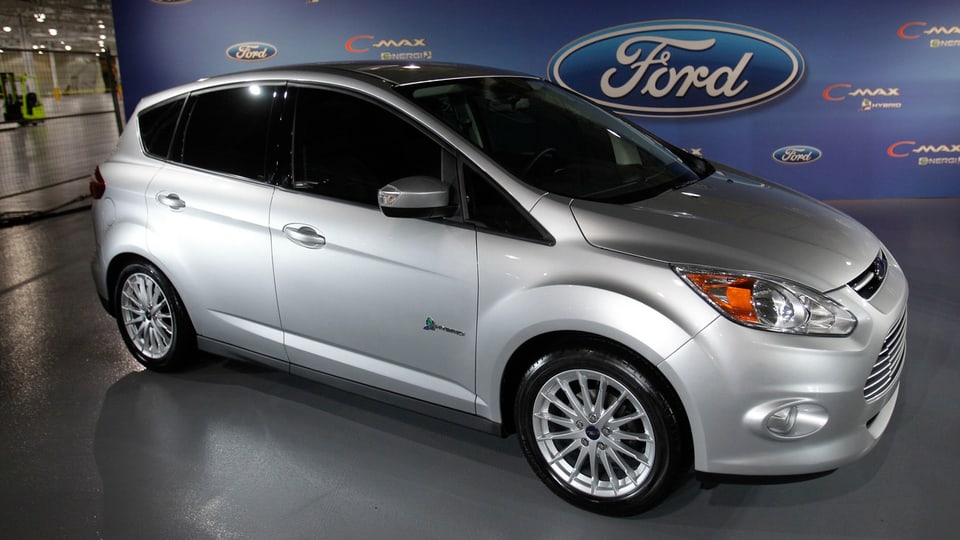 Ein silberner Ford-Wagen, es ist das vom Rückruf betroffene Modell. Dahinter ein grosses Ford-Logo, es steht offenbar in einer Garage. 