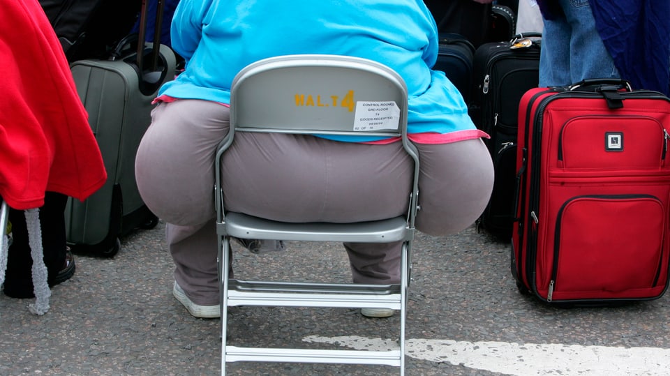 übergewichtige Person auf einem Stuhl von hinten