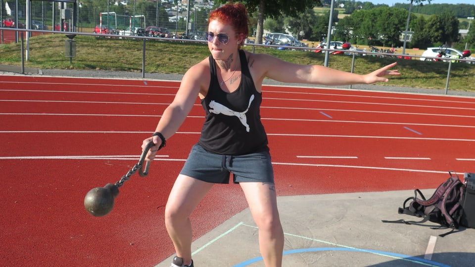 Eine Frau wirft eine Distance-Kugel auf einem Sportplatz.