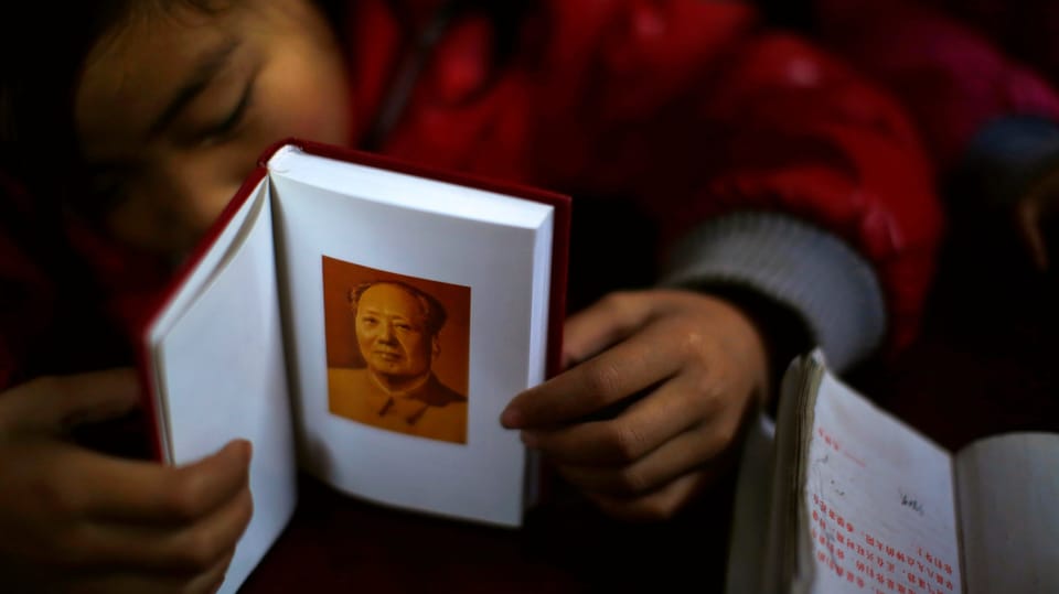 Chinesisches Mädchen hält Buch, darin ein Bild von Mao.