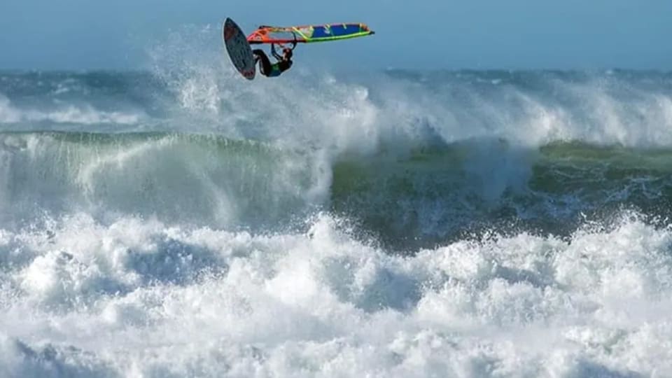 Ein Windsurfer fliegt über den riesigen Wellen im Mittelmeer.
