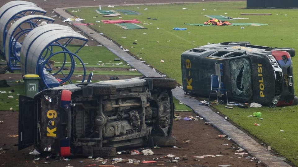 Zwei zerstörte Polizeiautos in mitten des Stadions.