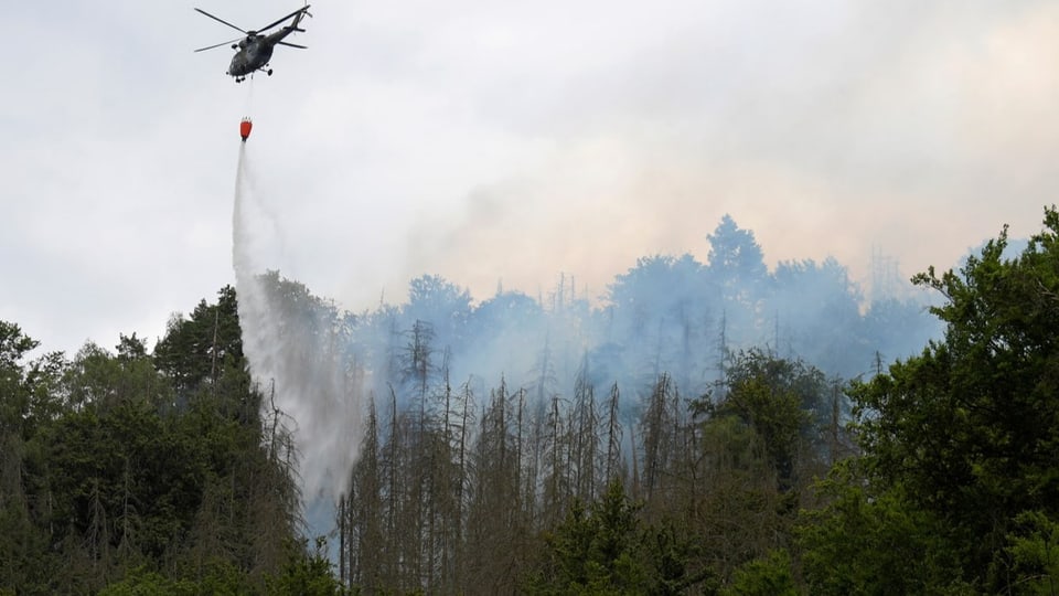 Ein Helikopter löscht Teile des Waldbrandes.