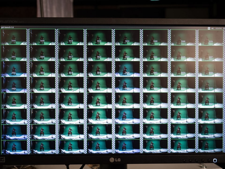 Ein grosser Monitor, darauf 8 mal 8 briefmarkengrosse Bildchen, das die Sicht jeder Kamera zeigt.