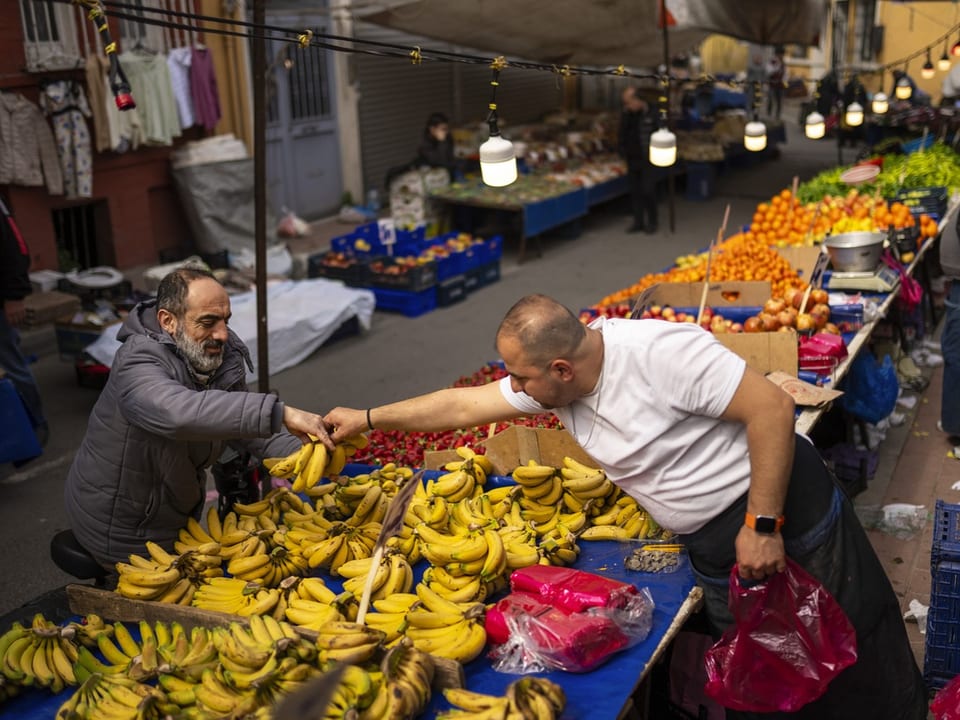 Eine Verkaufssituation in der Türkei: Ein Gemüse- und Früchtehändler übergibt dem Käufer ein paar Bananen. 