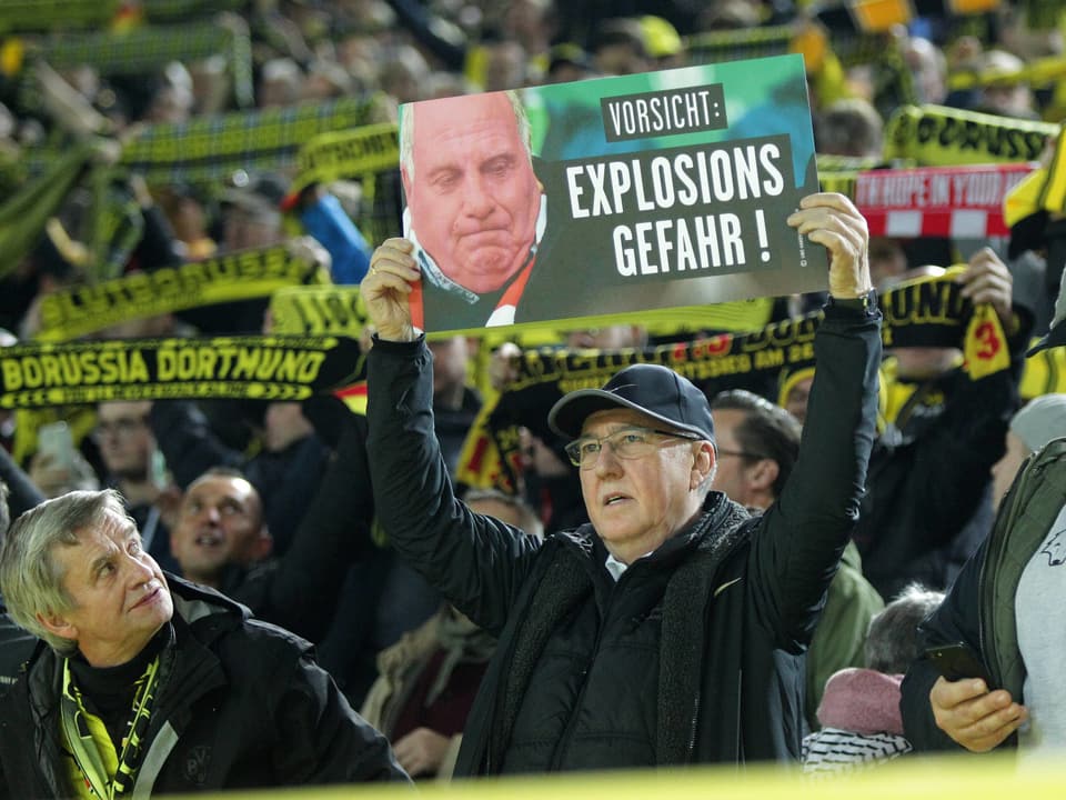 Ein Fan von Dortmund hält ein Schild mit dem Gesicht von Bayern-Präsident Uli Hoeness in die Luft.