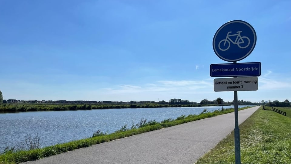 Schild an Strasse neben Kanal