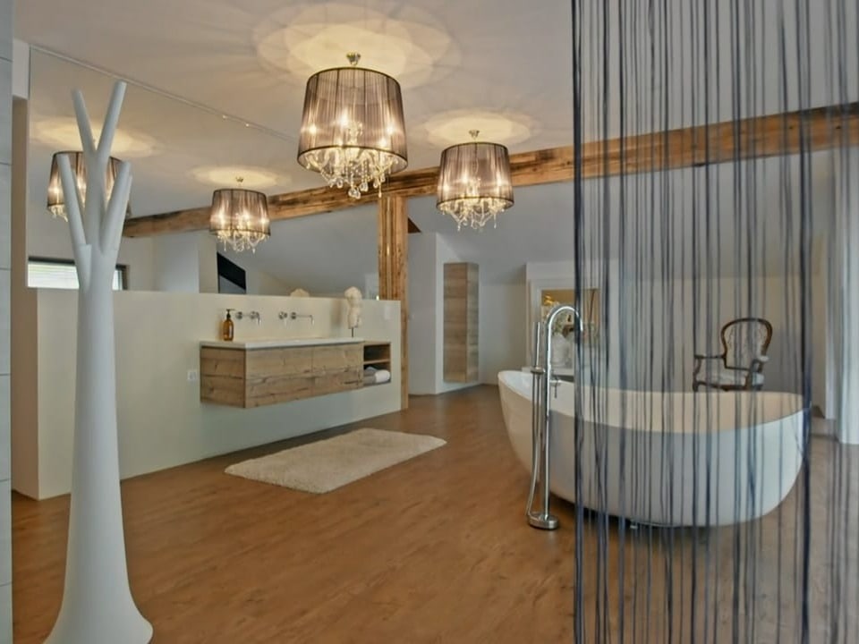 Ein grosses Badezimmer mit einer Badewanne und popmösen Lampen an der Decke.