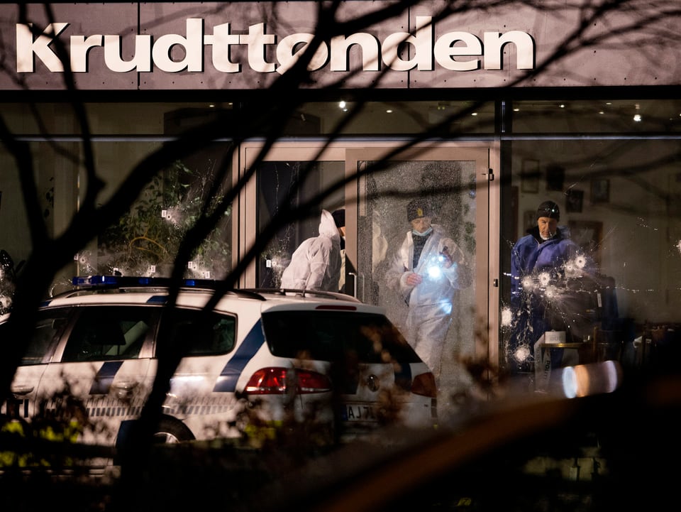 Forensiker sichern Spuren im Kulturcafé Krudttønden, hinter zerschossenen Fensterscheiben.