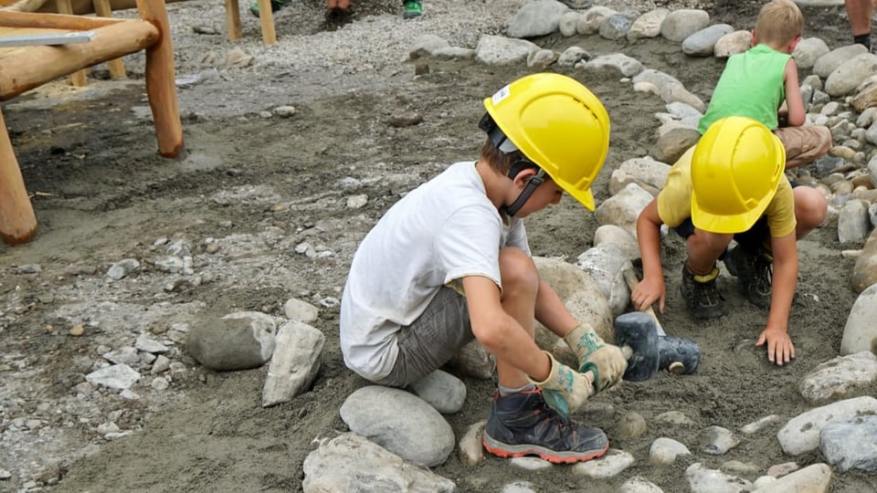 Kinder mit Bauhelmen legen Steine