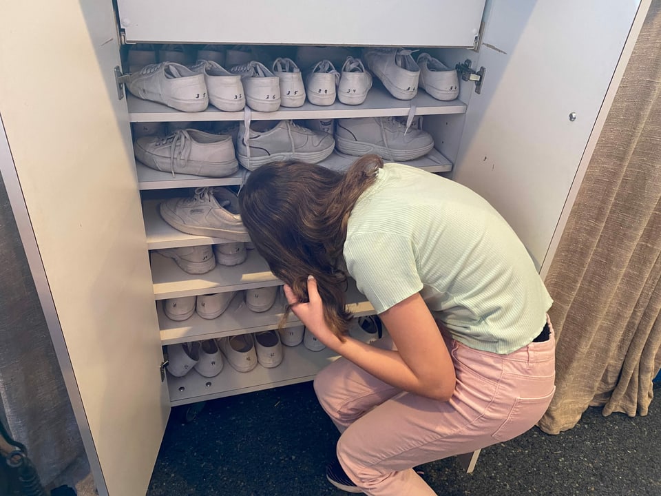 Sarah sucht sich ihre weissen Schuhe aus dem Schrank raus.