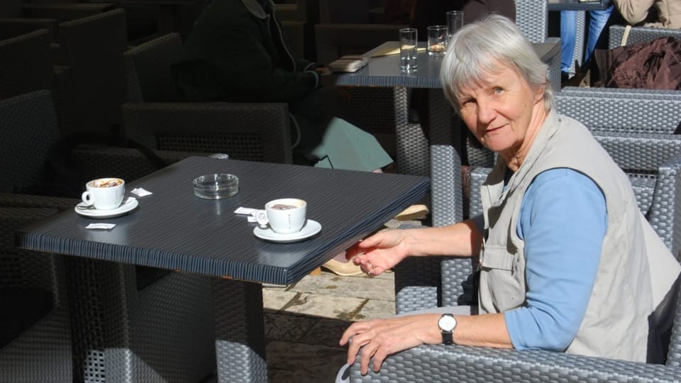 Ältere Frau sitzt draussen im Kaffee