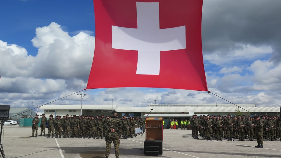 Schweizer Fahne und Soldaten auf Flugplatz.