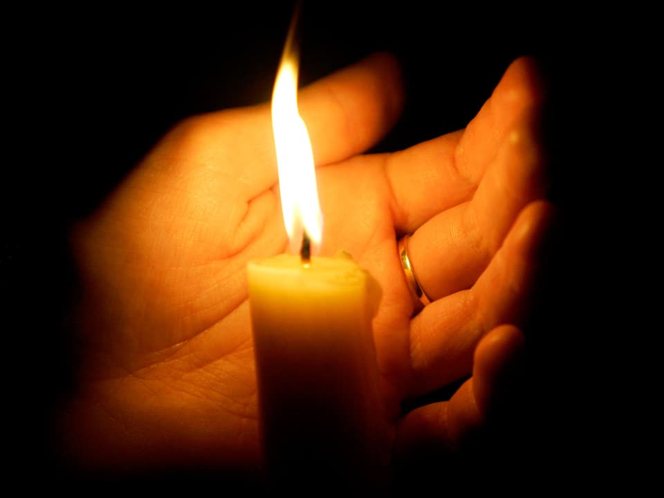 Eine Hand hält eine Kerze.