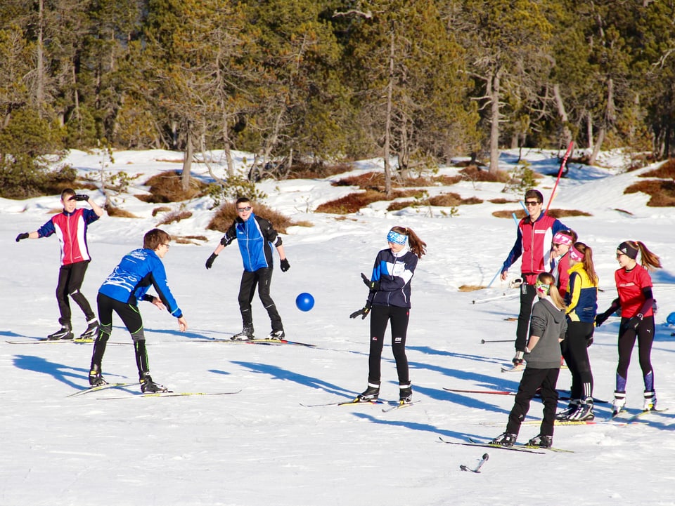 Jugendliche machen ein Ballspiel auf Langlaufskiern.