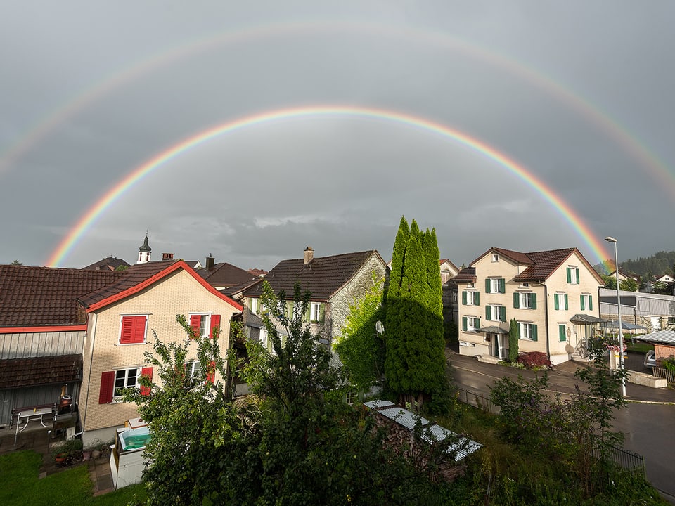 Doppelter Regenbogen über Häusern.