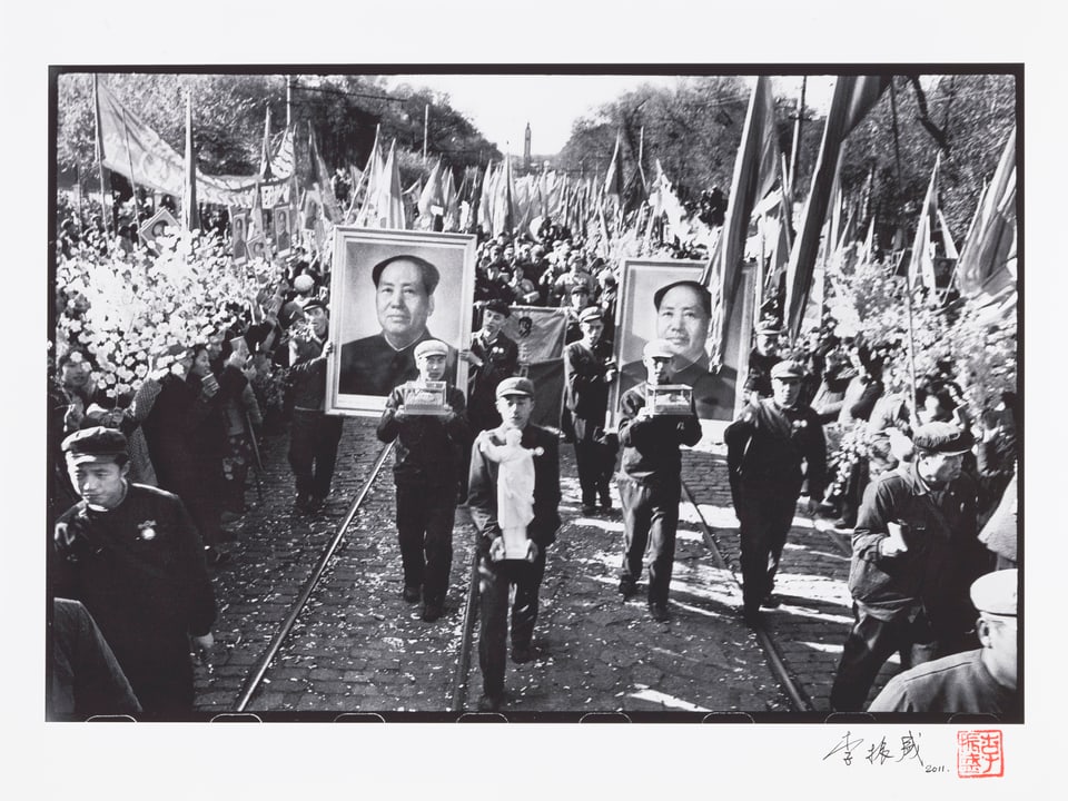 Parade, zuforderst tragen zwei Uniformierte je eine Mango in Glasvitrine.