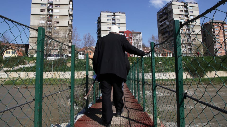 Ein Mann überquert eine Brücke in Mitrovica.