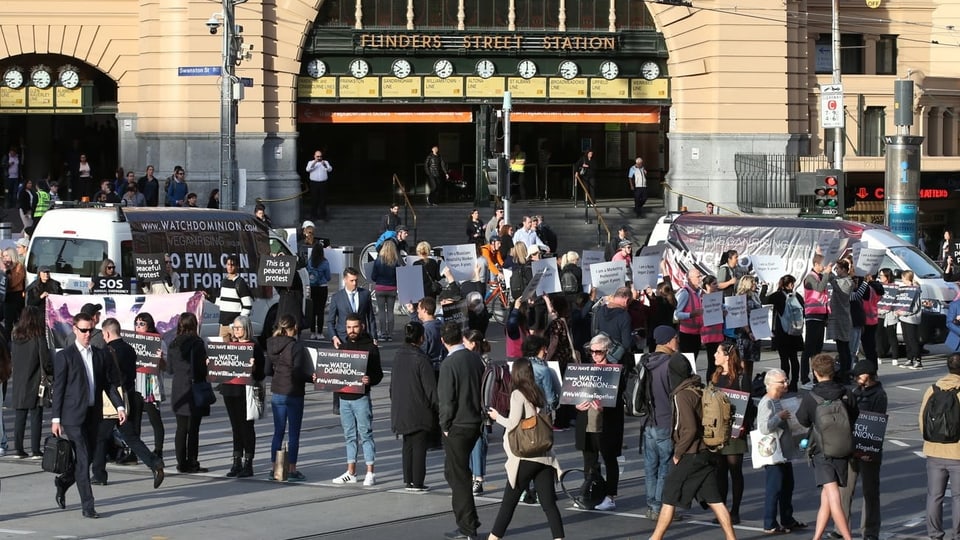 Personen mit Plakaten vor einem Jugendstil-Gebäude.