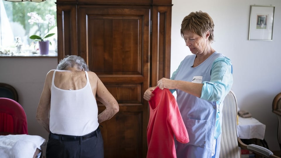 Spitexmitarbeiterin hilft einer alten Frau