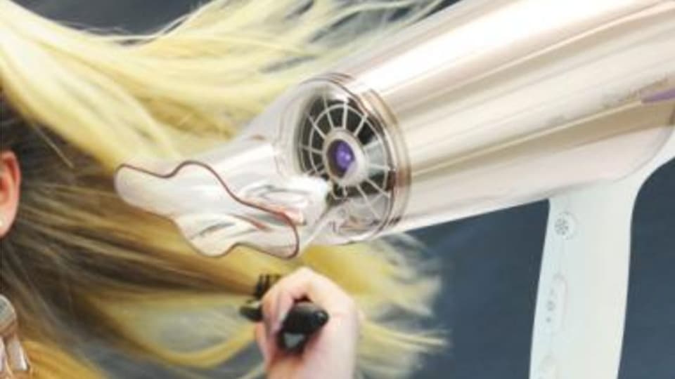 Haarfön, im Hintergrund blondes langes Haar.