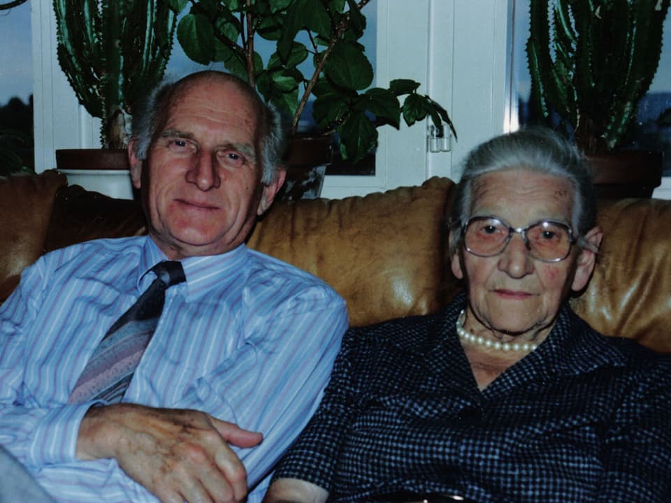 Ein Mann und eine Frau sitzen nebeneinander auf einem braunen Ledersofa.