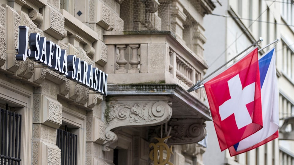 Schriftzug der Privatbank J. Safra Sarasin mit Schweizer Flagge.