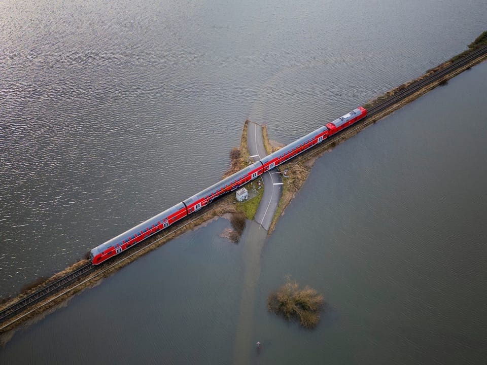 A train travels through a flood-affected landscape.  Bird's eye view photo.