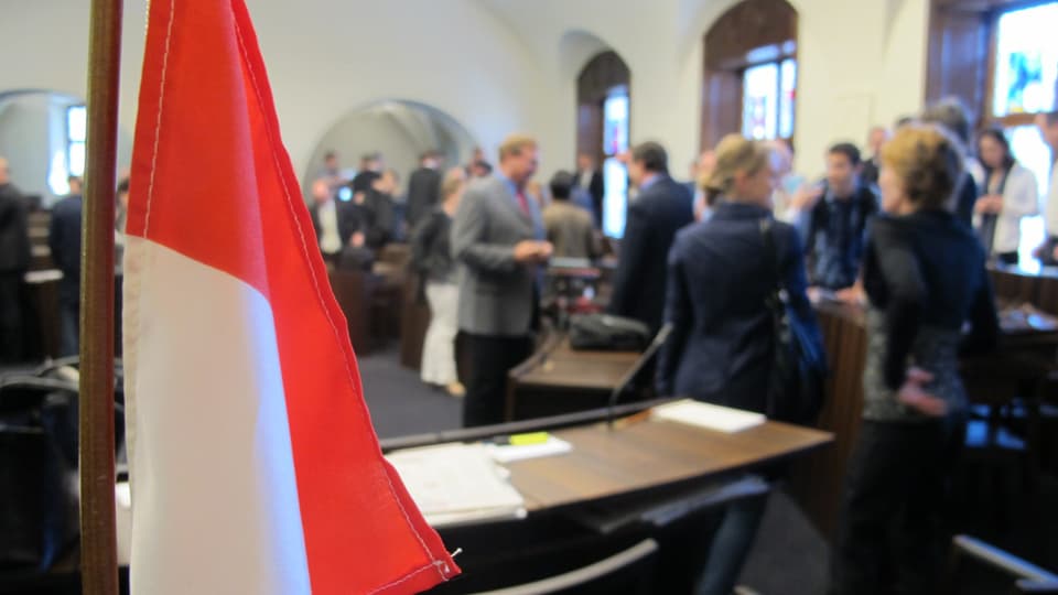 Parlamentarier im Kantonsratssaal in Solothurn am Diskutieren. Im Vordergrund eine Kantonsflagge.