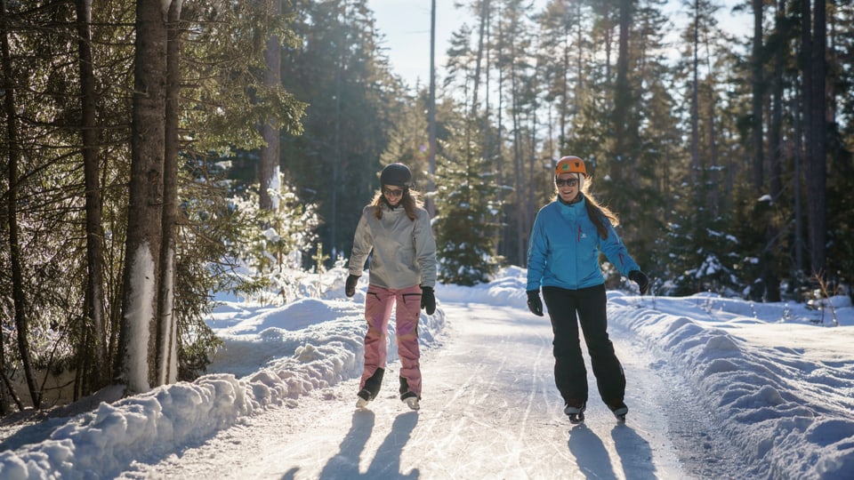 Zwei Frauen mit Schlittschuhen auf dem Eisweg.
