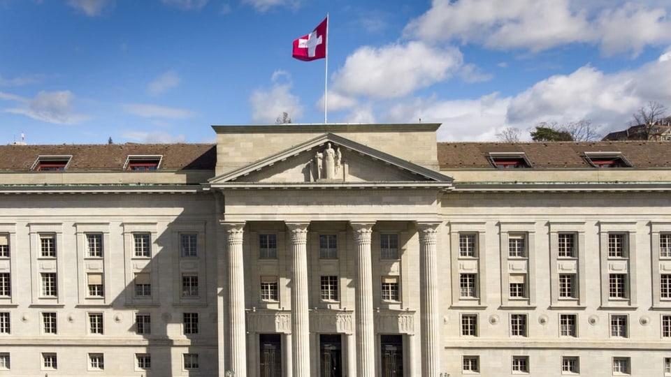 Auf dem Bild sieht man das Bundesgericht mit wehender Schweizer Fahne unter leicht bewölktem Himmel
