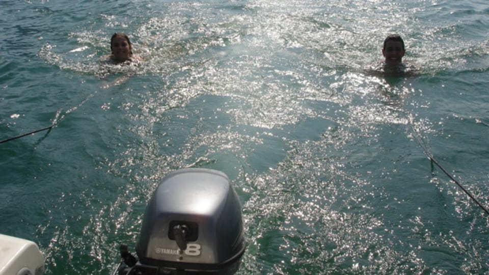 Schwimmende Kinder hinter Motorboot.