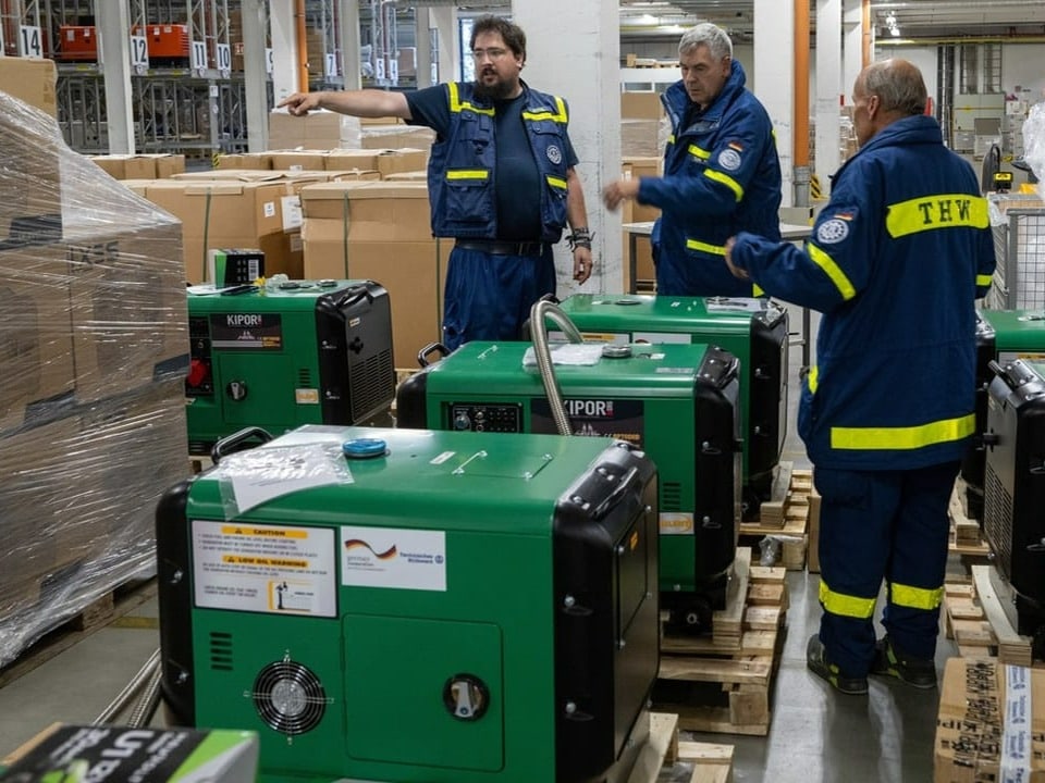 Drei Angestellte des deutschen Technischen Hilfswerks bereiten Stromaggregate für Libyen vor.