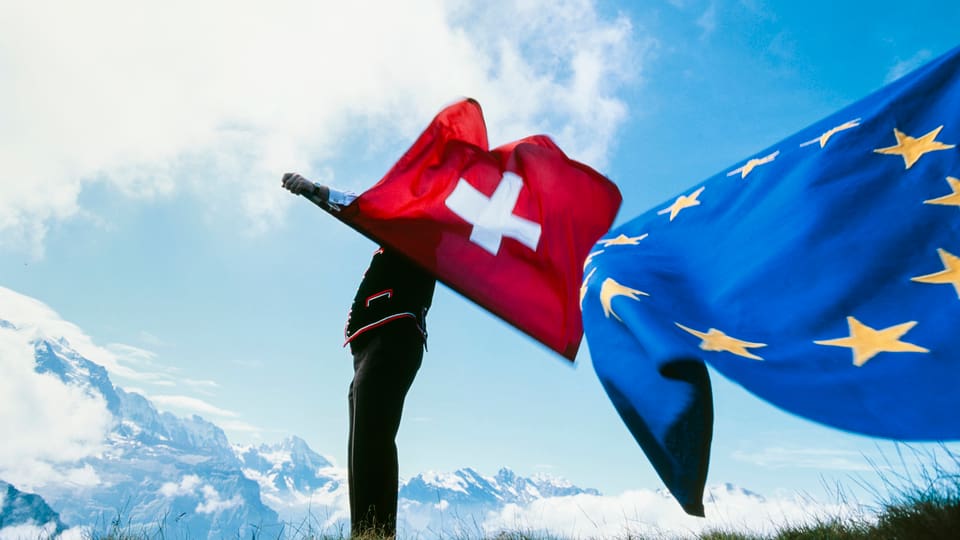 Symbolbild: Ein Fahnenschwinger schwingt eine Schweizer Fahne, ebenfalls im Bild, eine EU-Fahne.