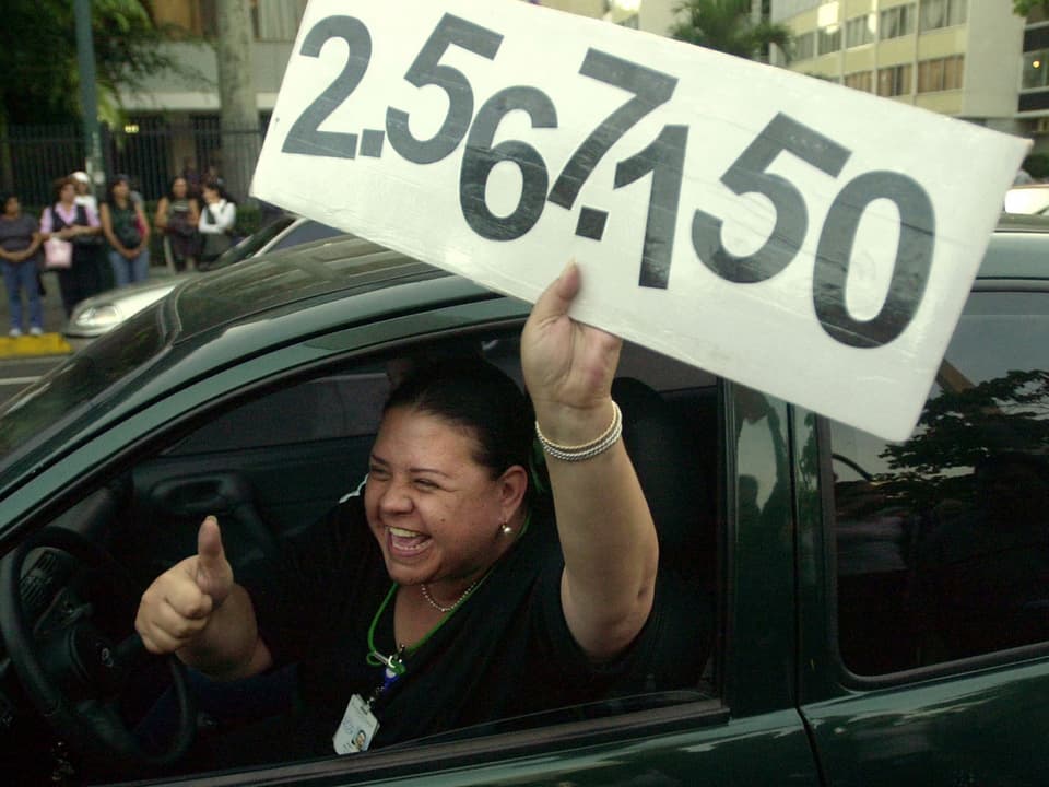 Eine Frau hält ein Schild mit der Zahl 2'567'150 aus einem Auto und streckt den Daumen in die Höhe