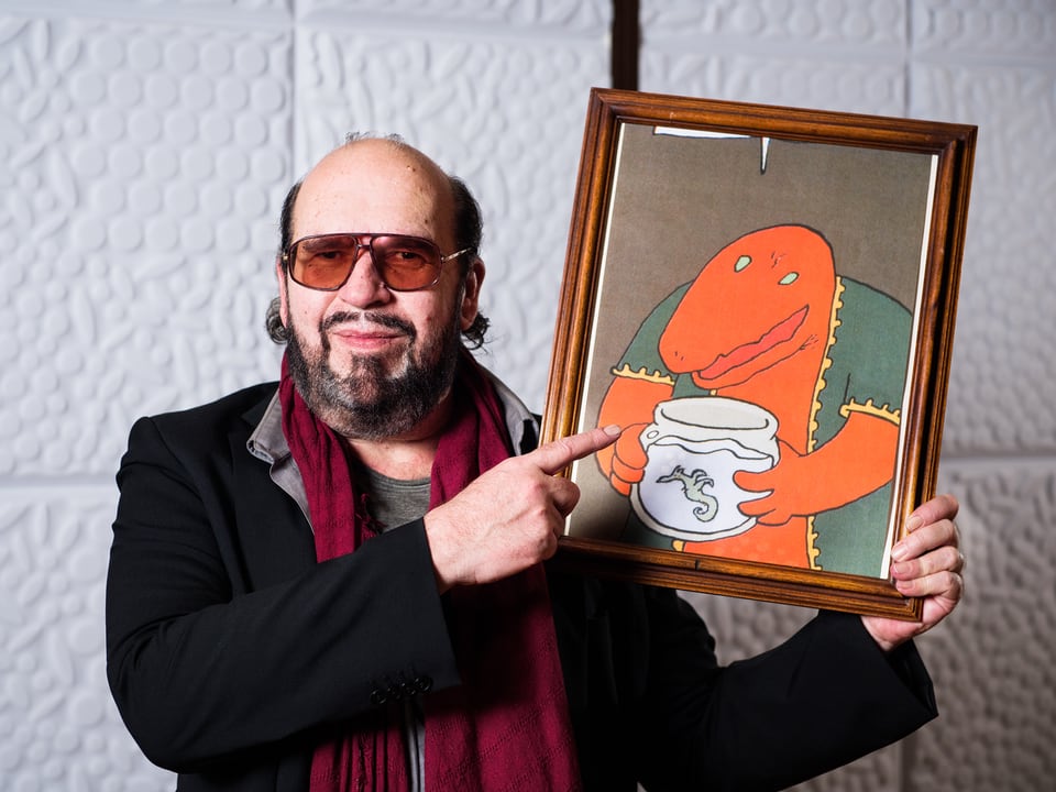 Hörspiel-Sprecher Jörg Döring zeigt auf ein Bild des Comic-Drachen Marvin.
