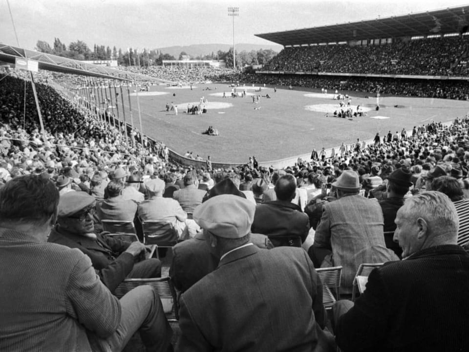 Historische Aufnahme: Menschen sitzen in einem Stadion