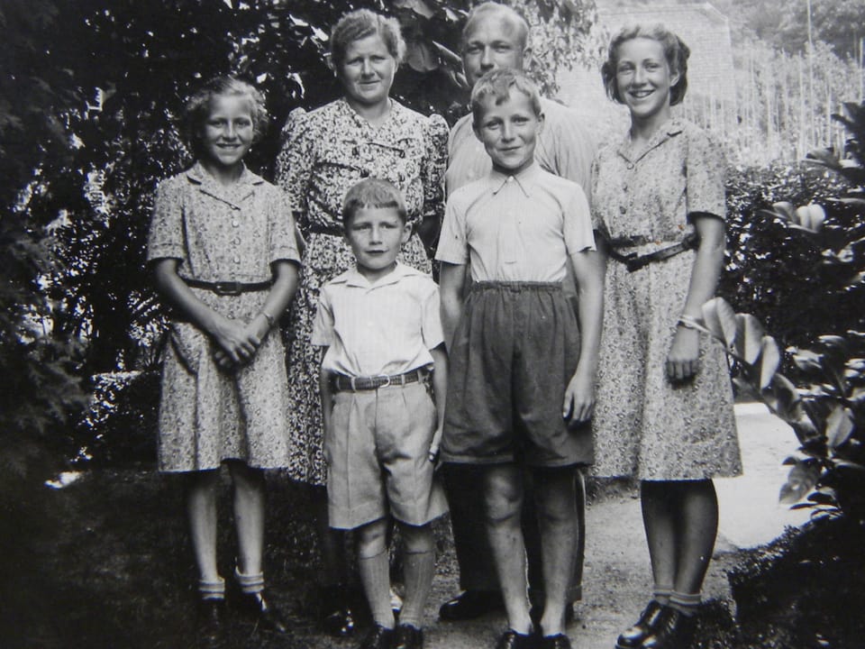 Schwarz-Weiss Fotografie mit Eltern, die hinter ihren vier Kindern stehen.