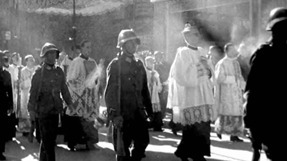 Eine Prozession mit katholischen Würdenträgern und Soldaten.