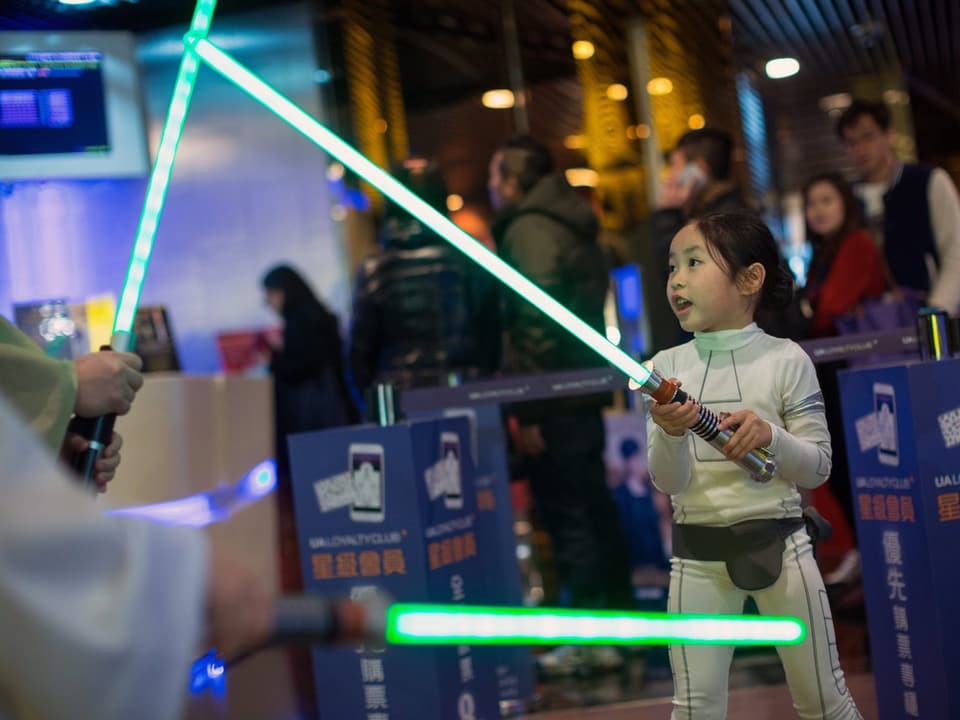 Ein chinesisches Kind mit einem Jedi-Schwert.