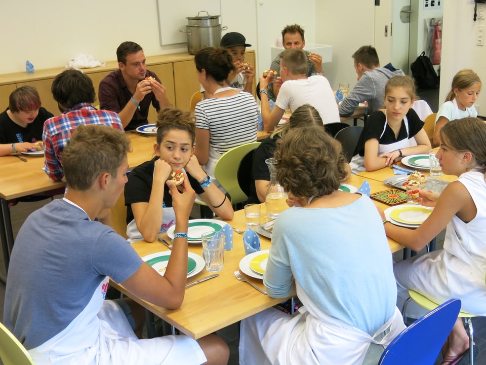 Die Jugendlichen und die Betreuer sitzen am Tisch und essen.