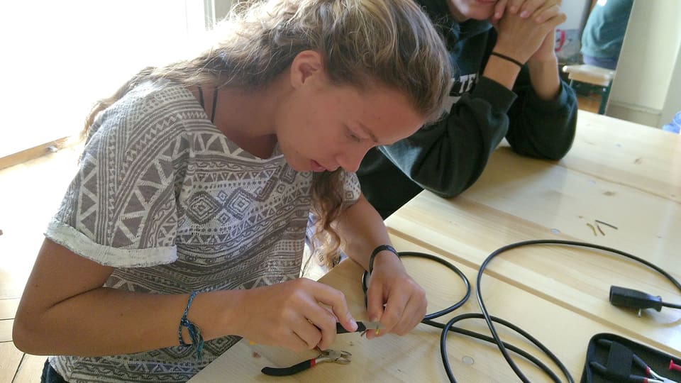 Eine junge Frau arbeitet mit einem Elektrokabel.