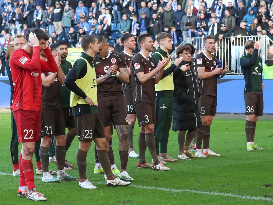 Spieler des FC St. Pauli stehen nach der ersten Liganiederlage in dieser Saison vor dem Gästeblock.