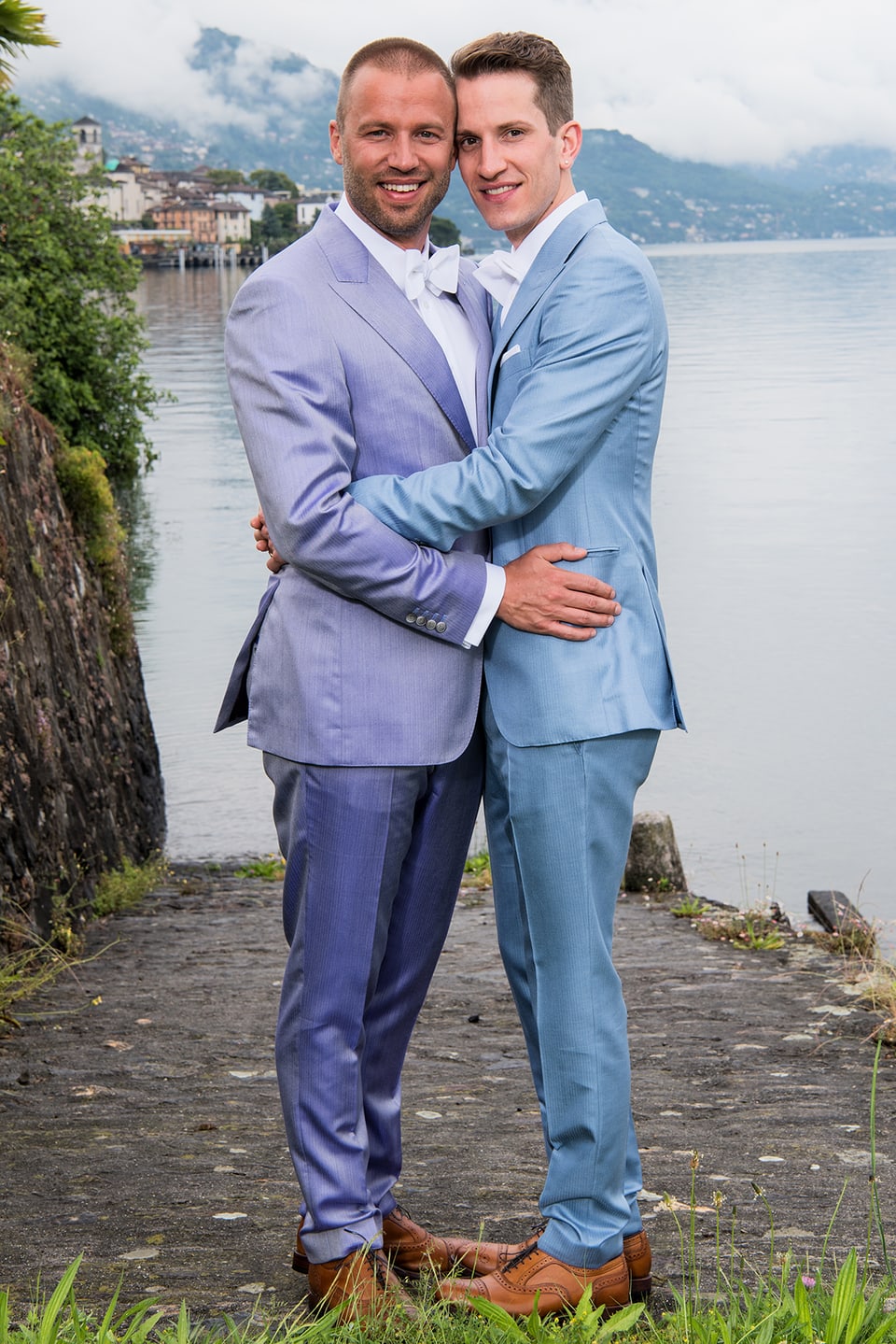 Jonny Fischer und Ehemann total, umarmen sich. Beide im blauen Smoking mit weisser Fliege. 