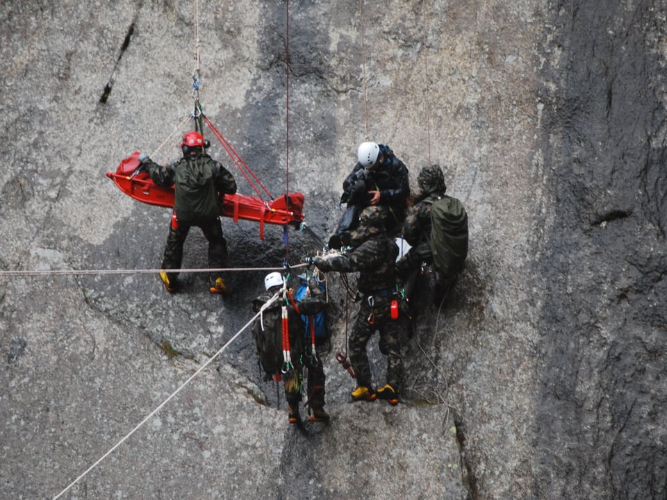 Drei Rettungshelfer, ein Kameramann und Nik Hartmann auf der Trage mitten in der fast. senkrechten Felswand. 