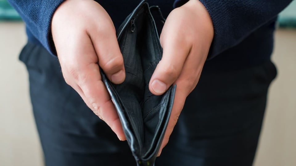 Eine Person zeigt eine leere Brieftasche